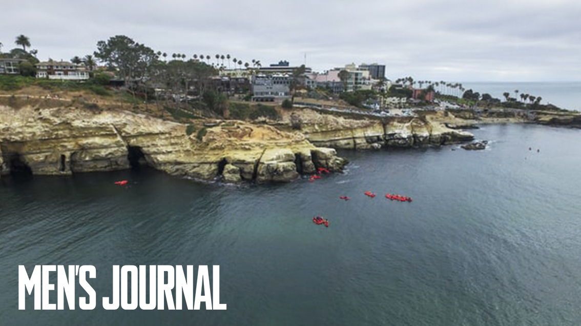 Drone footage of the La Jolla Seven Sea Caves from above, on a gloomy day. there are several red kayaks in the water